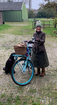 Customer wearing her waxed cotton Compass skirt holding her push bike with her black lab siting next to them.