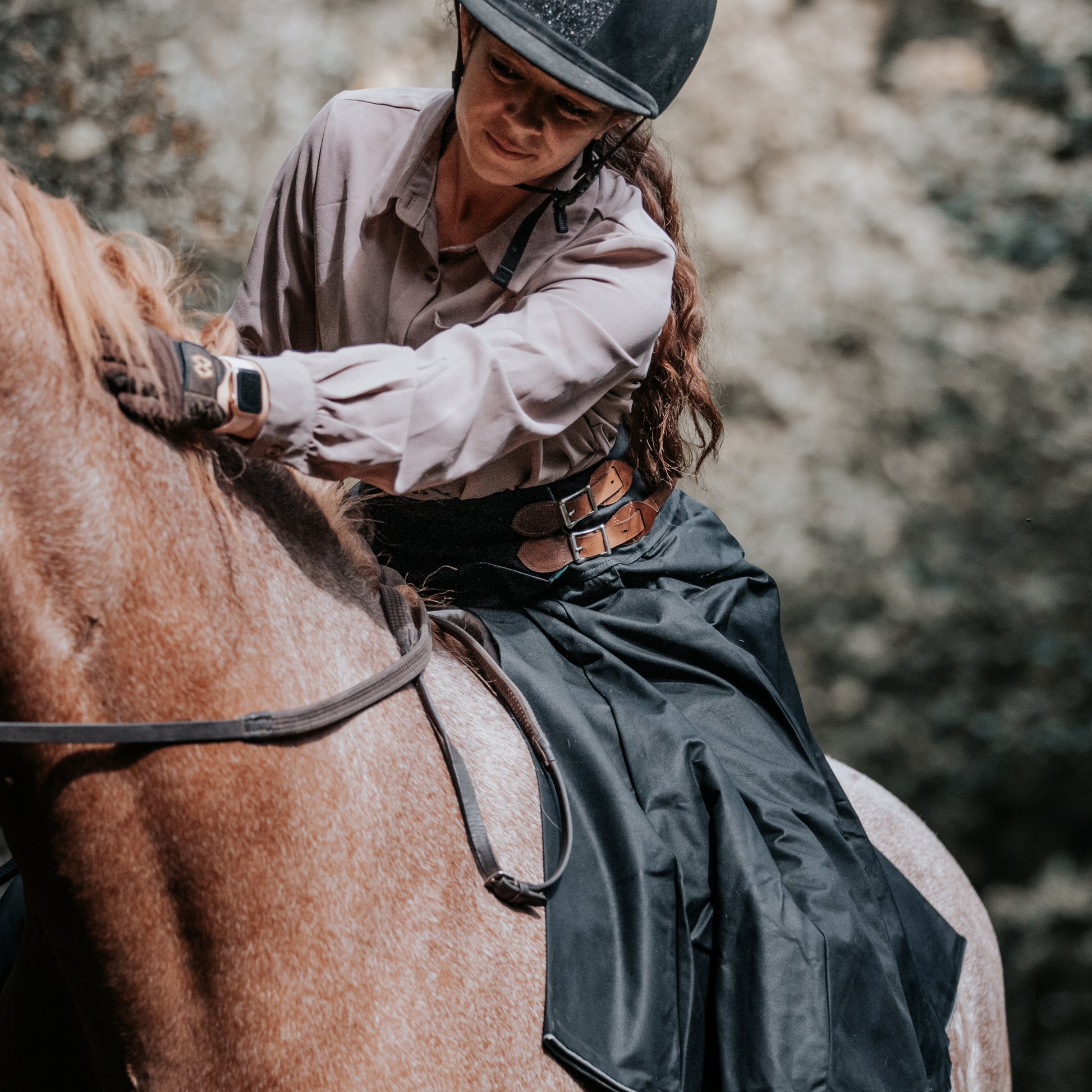 Rider stroking her horses neck while wearing a black wax hand crafted riding habit.
