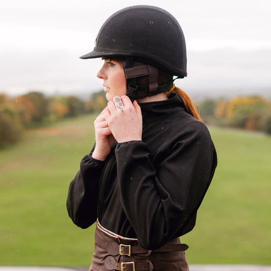 lady doing up her riding hat featuring our brown ear warmers