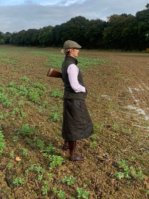 Customer wearing her handcrafted waterproof habit, stood in a muddy feild with her shotgun ready for the day.