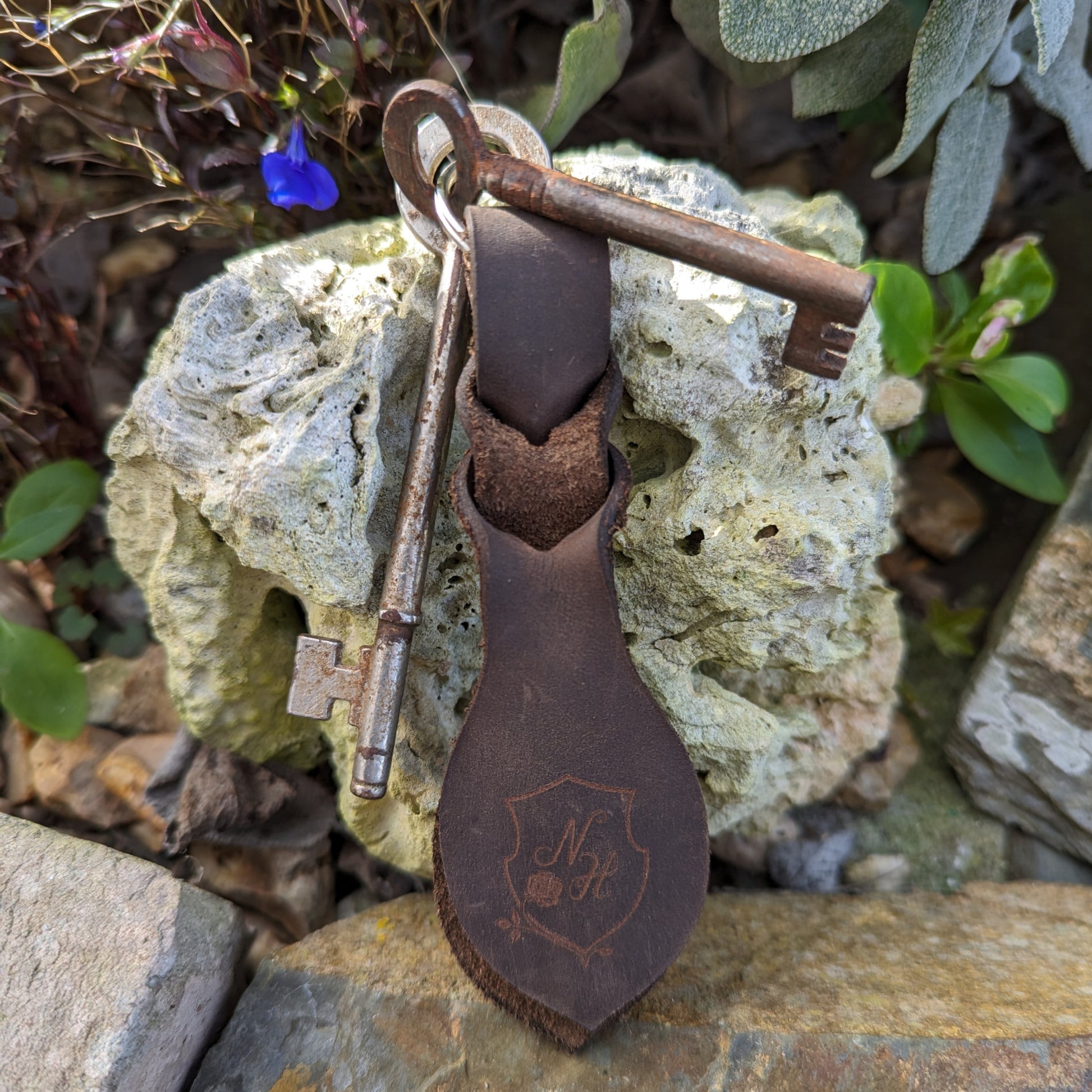 Leather king ring resting on a stone with two old keys.