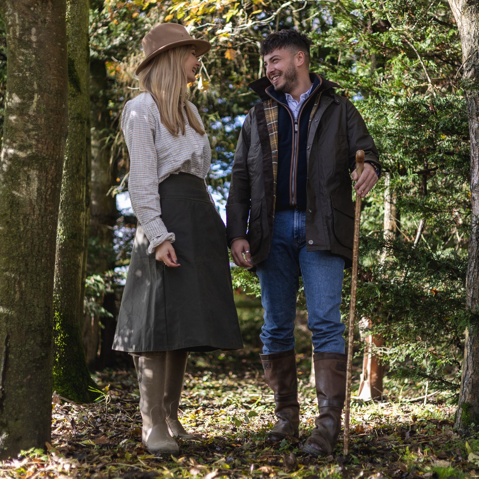 A couple wearing country clothing while walking though woodlands, featuring our British-made habit.