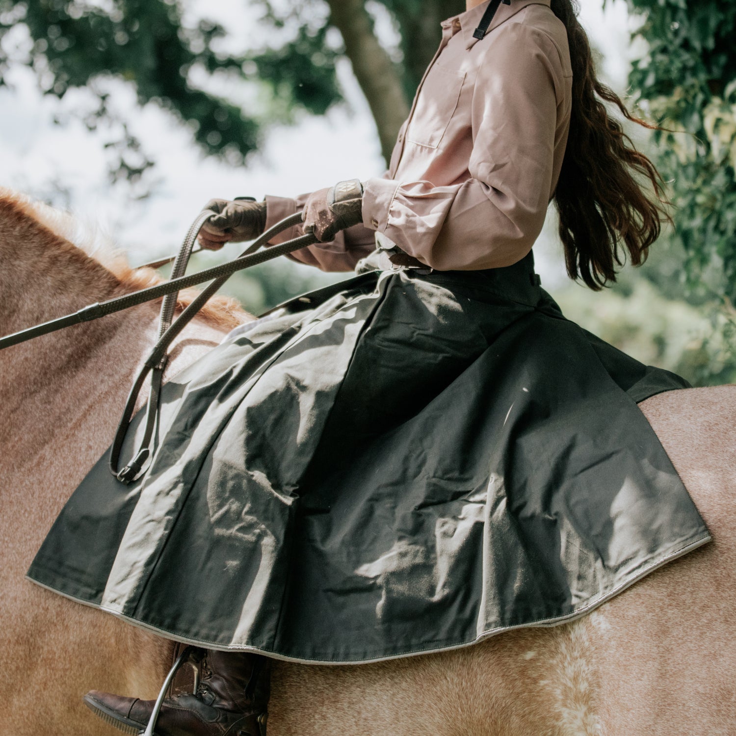 Side view of our British-made waterproof riding skirt in khaki green with dappled light across it.