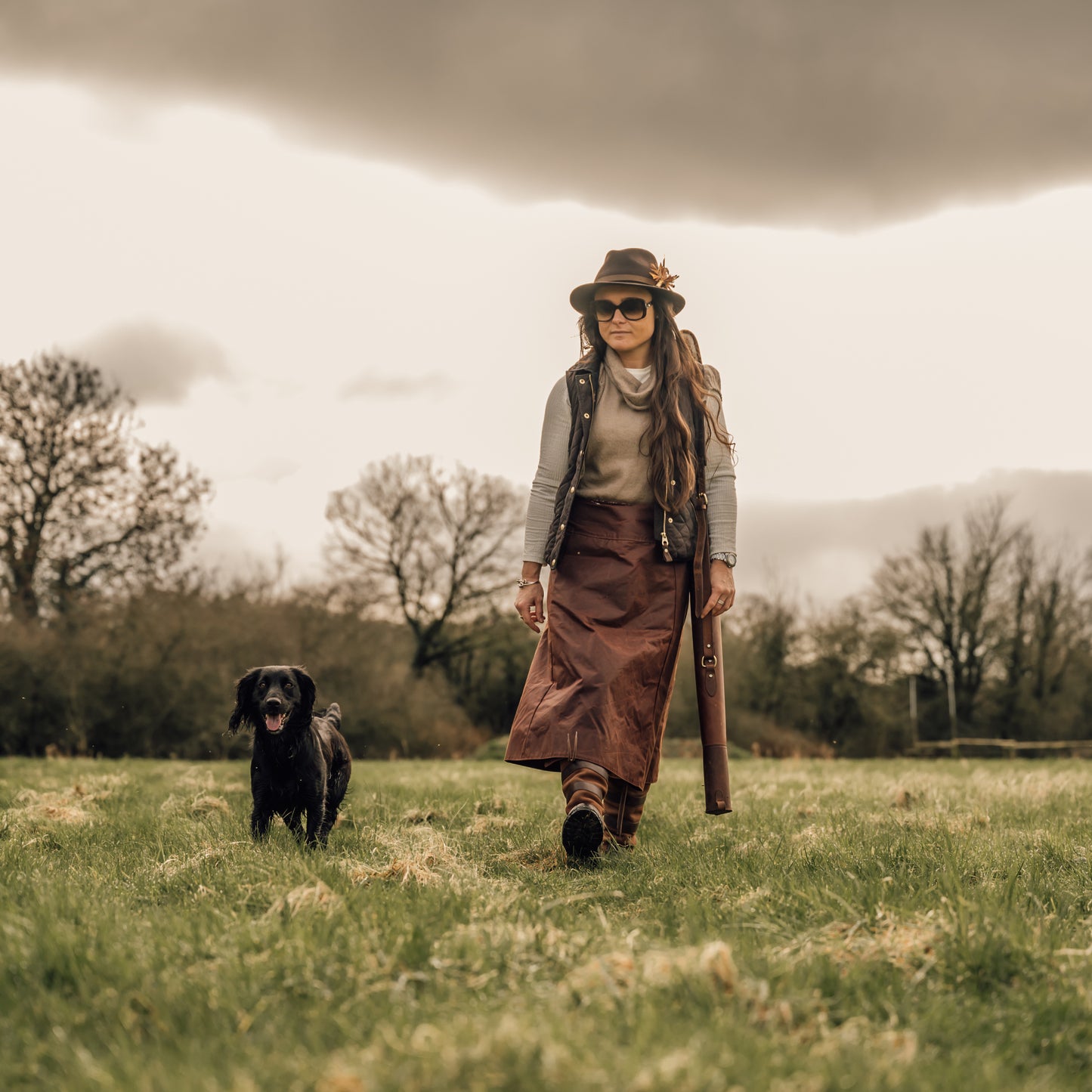 Handcrafted waterproof habit being worn while walking across a field with a black dog walking at heel.