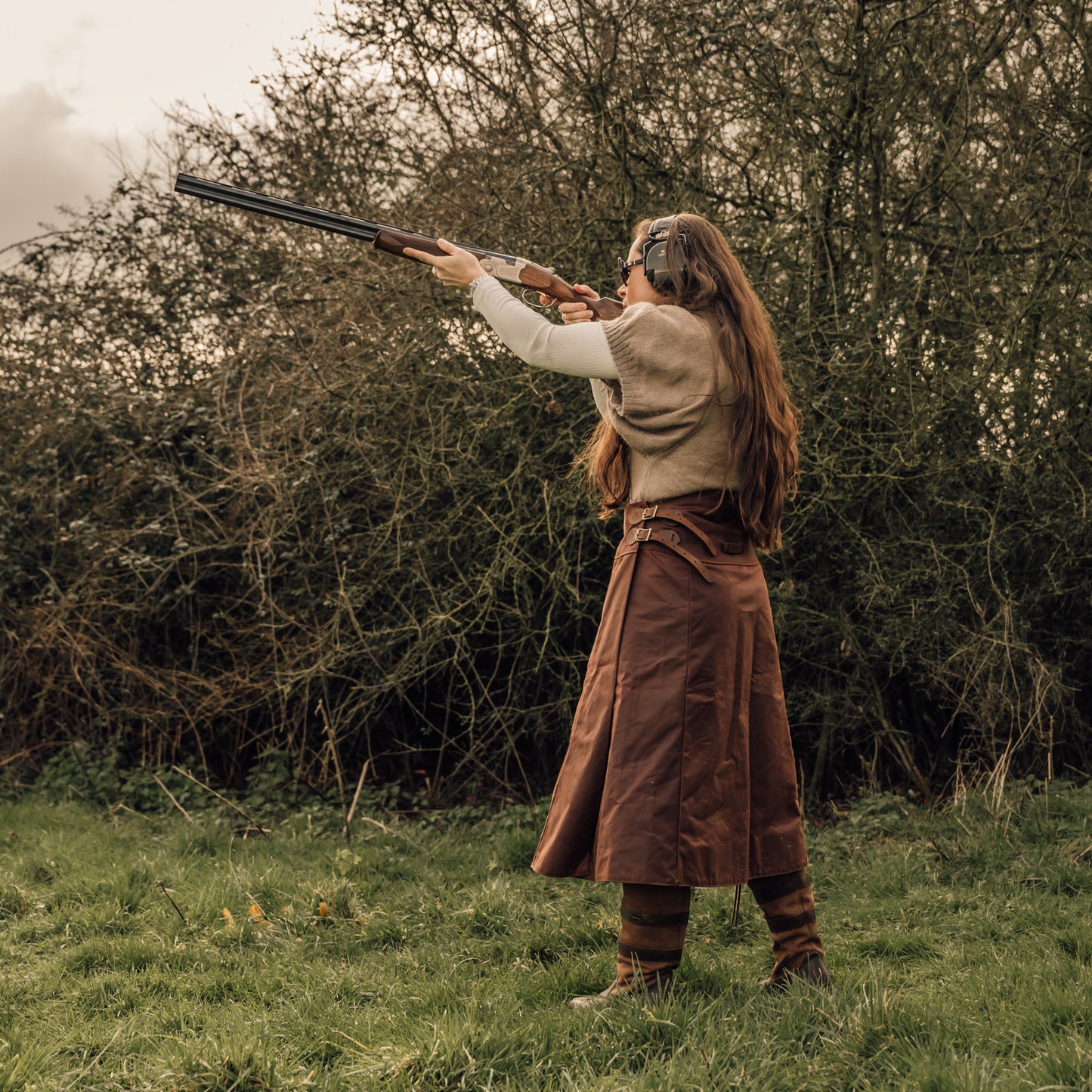 British made shooting skirt being worn by a woman stood shooting clays in a feild.