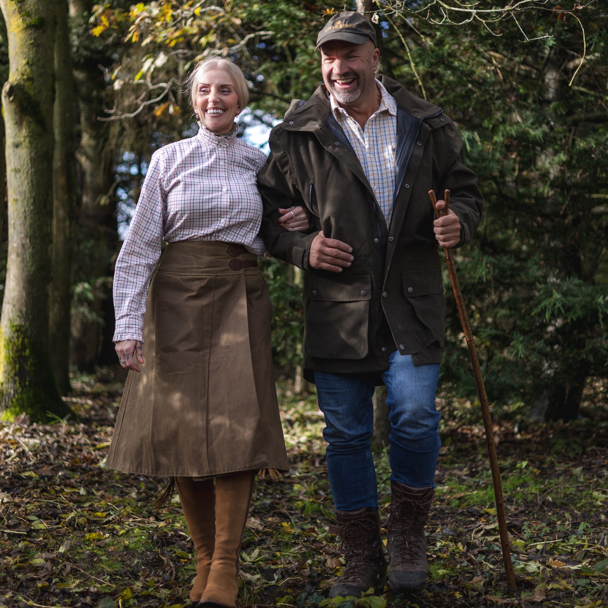 A coulpe laughing and walking though woodlands wearing our handcrafted waxed cotton habit.