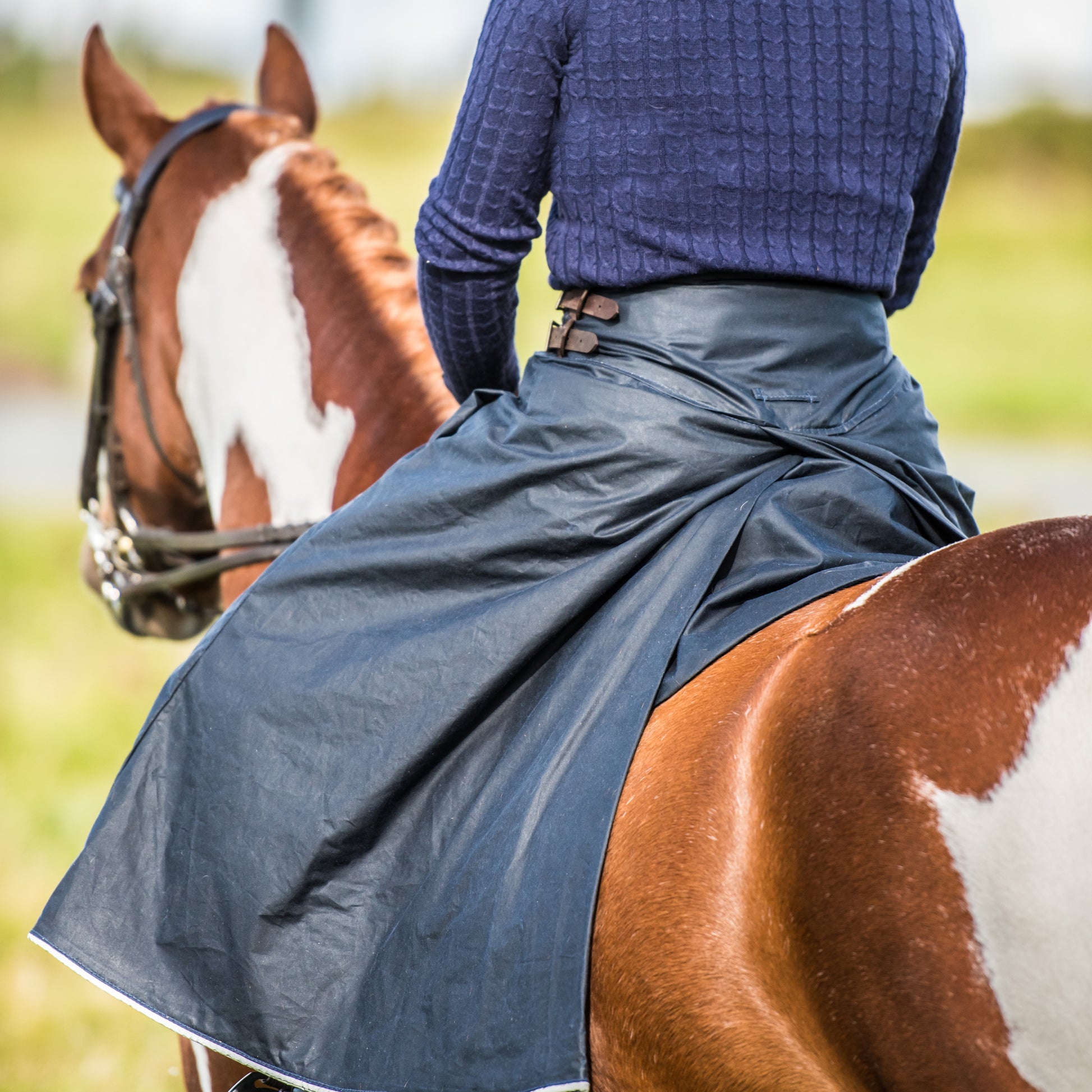 Woman wearing handcrafted riding habit in navy taken from behind to show our unique split design. countryside
