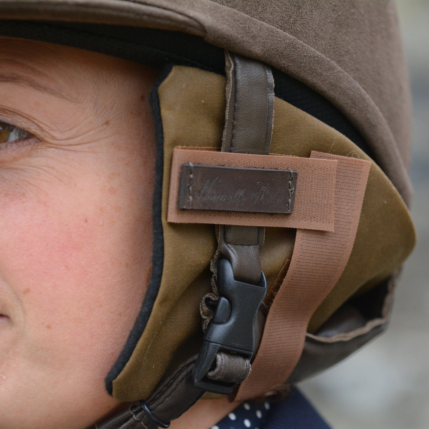 Handmade ear warmers attached in a riding hat being worn by a woman.