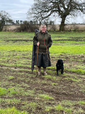 Customer wearing her bespoke shooting skirt while stood in a feild with her dog and shotgun, ready for the day ahead.