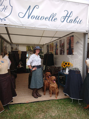 Customer stood in her Bespoke tweed compass habit on the Nouvelle Habit stand at The Game Fair, with her two red lab's.