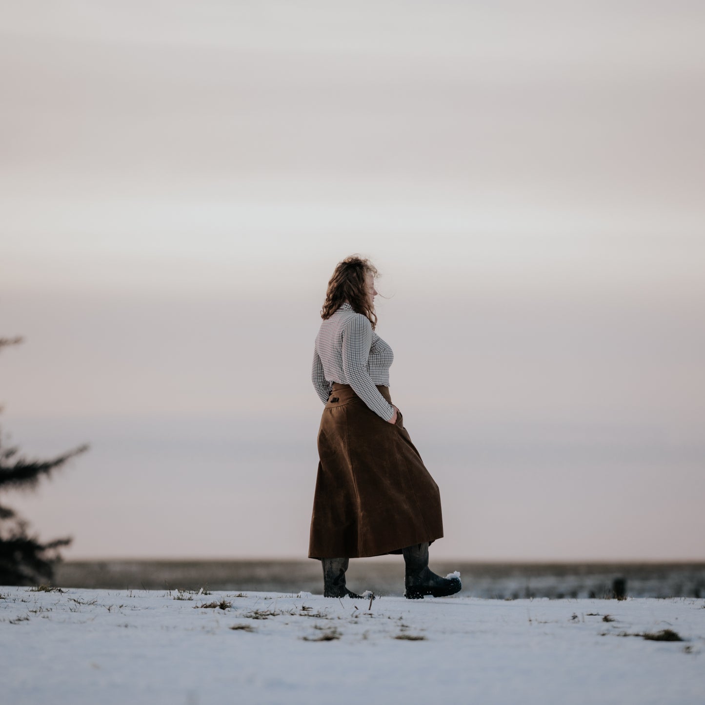 Woman walking though the snow wearing her handcrafted habit with her hands in her pocket.