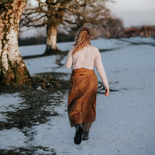 Lady walking away in the snow wearing her Tundra shooting skirt.