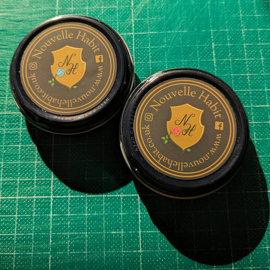 Two wax tin pots on a cutting matt in the studio with the sun on them.