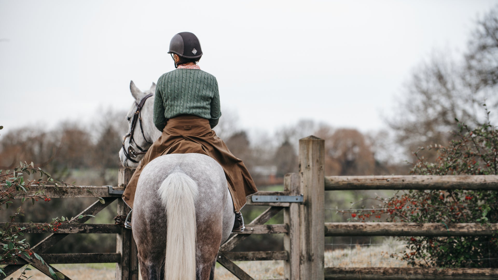 British-made waterproof riding skirt worn on a grey horse stood in a gateway