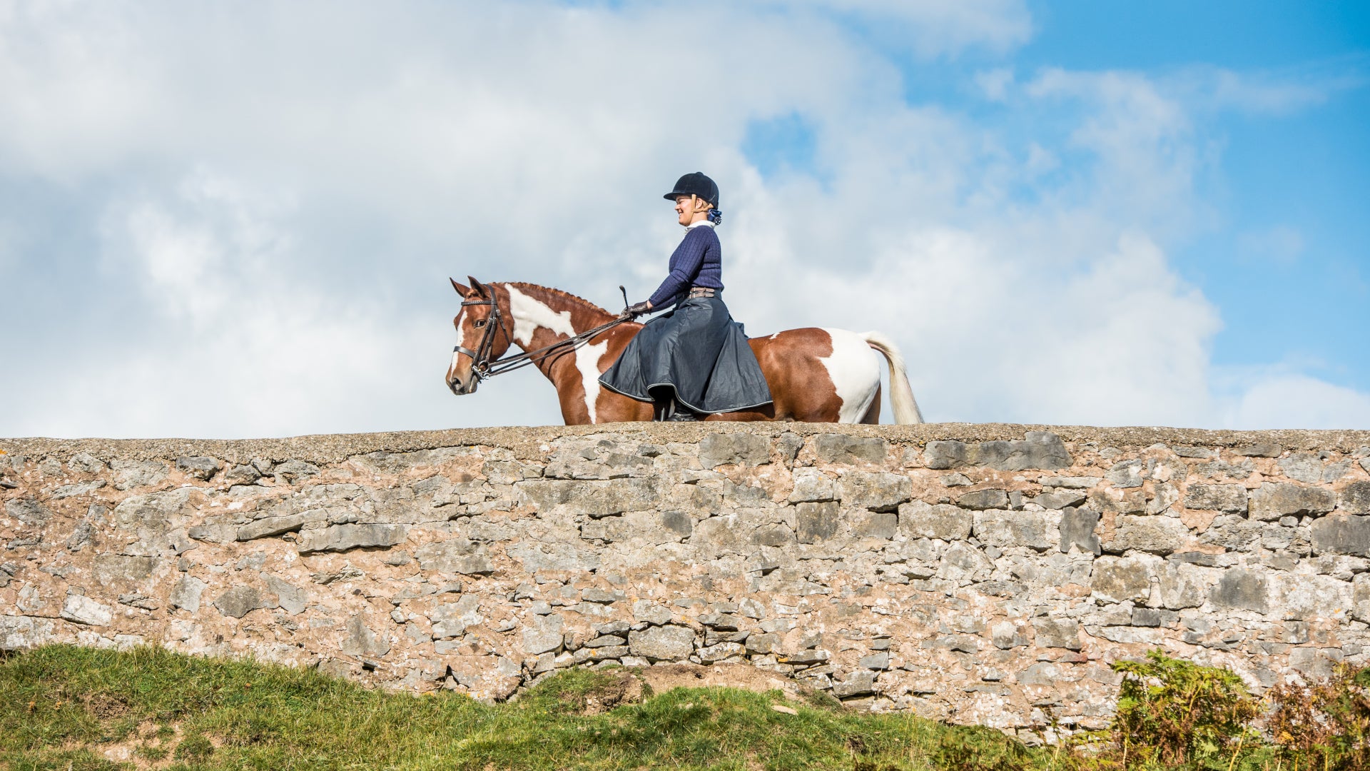 British-made waterproof riding habit worn while riding across a stone bridge.