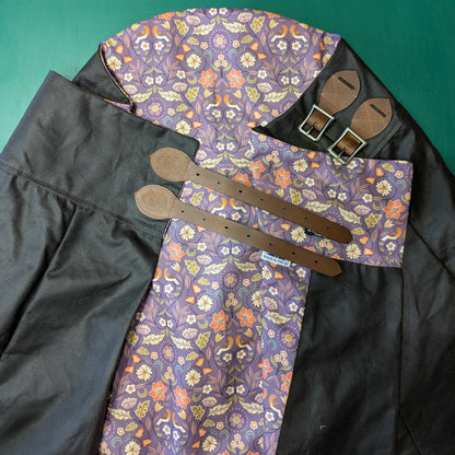 An areial view of the Isabella riding skirt folded to show off the Vinatge brown waxed cotton and the purple floral lining