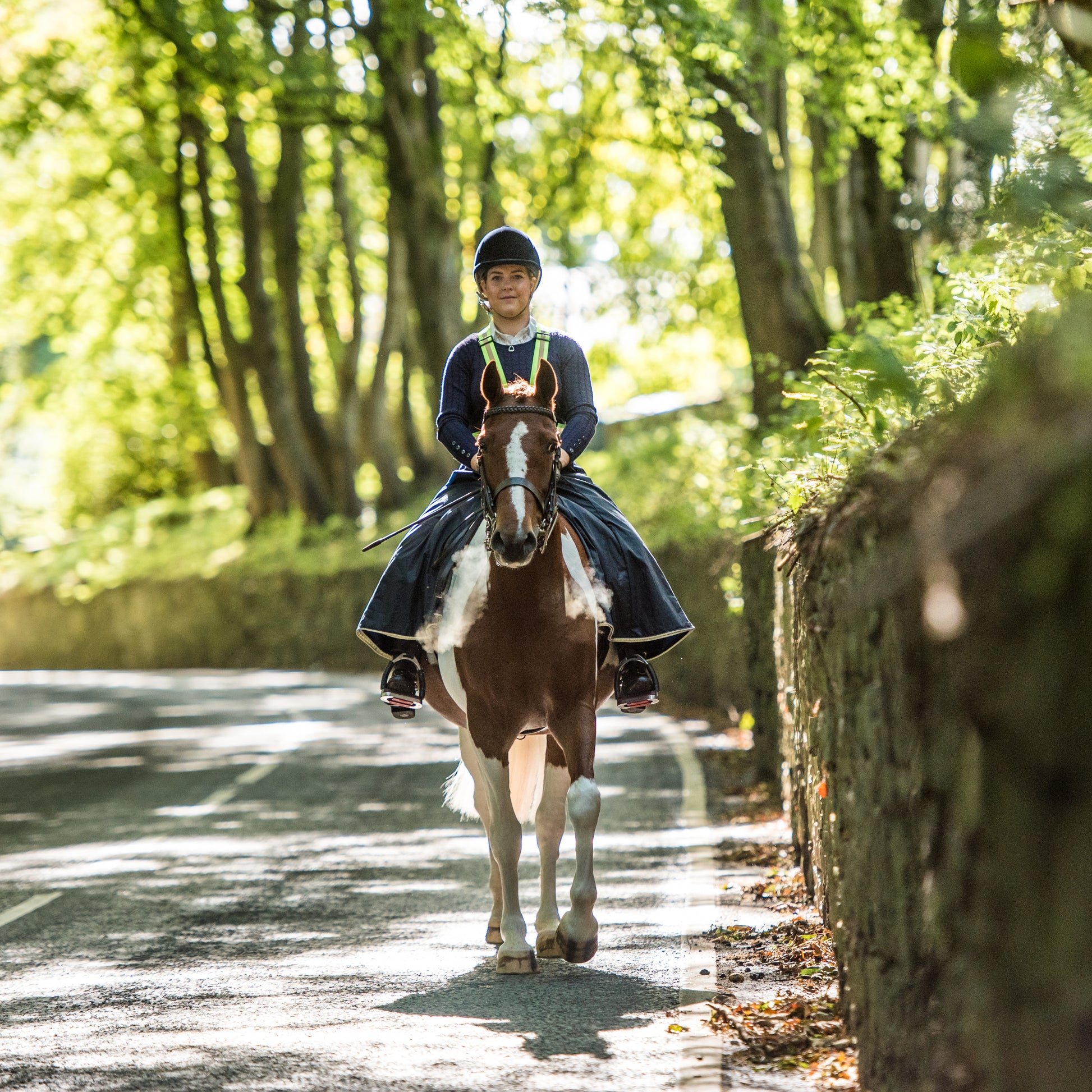 Woman wearing handcrafted riding habit on a country road in the cold air causing misty steam to come out of the horses nostrials.