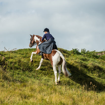 British made riding habit being worn while cantering up a steep slope while the rider is in a forward pose position.
