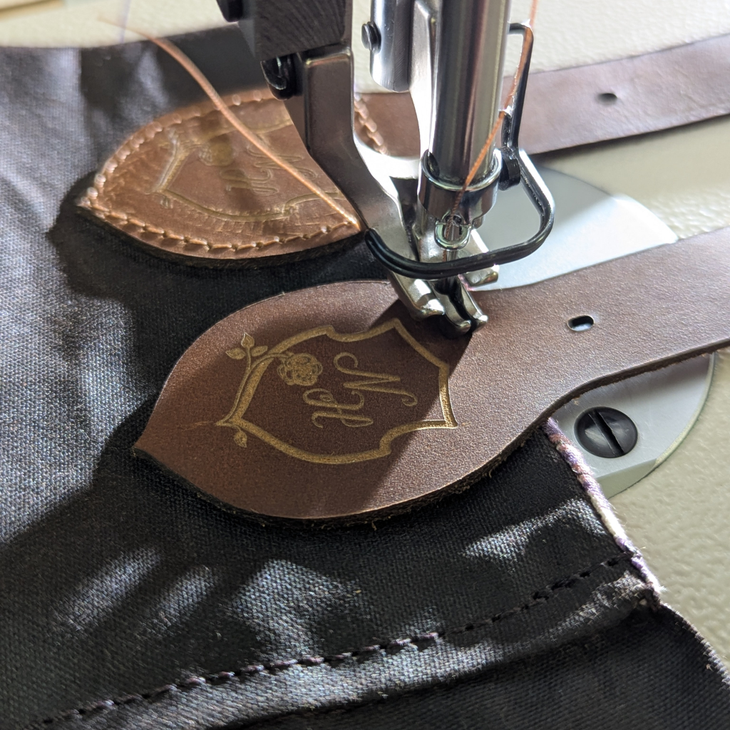 Close up of the leather buckles being sewn onto a waxed cotton habit.